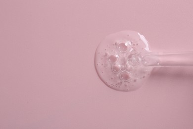 Pipette with cosmetic serum on pink background, top view. Space for text