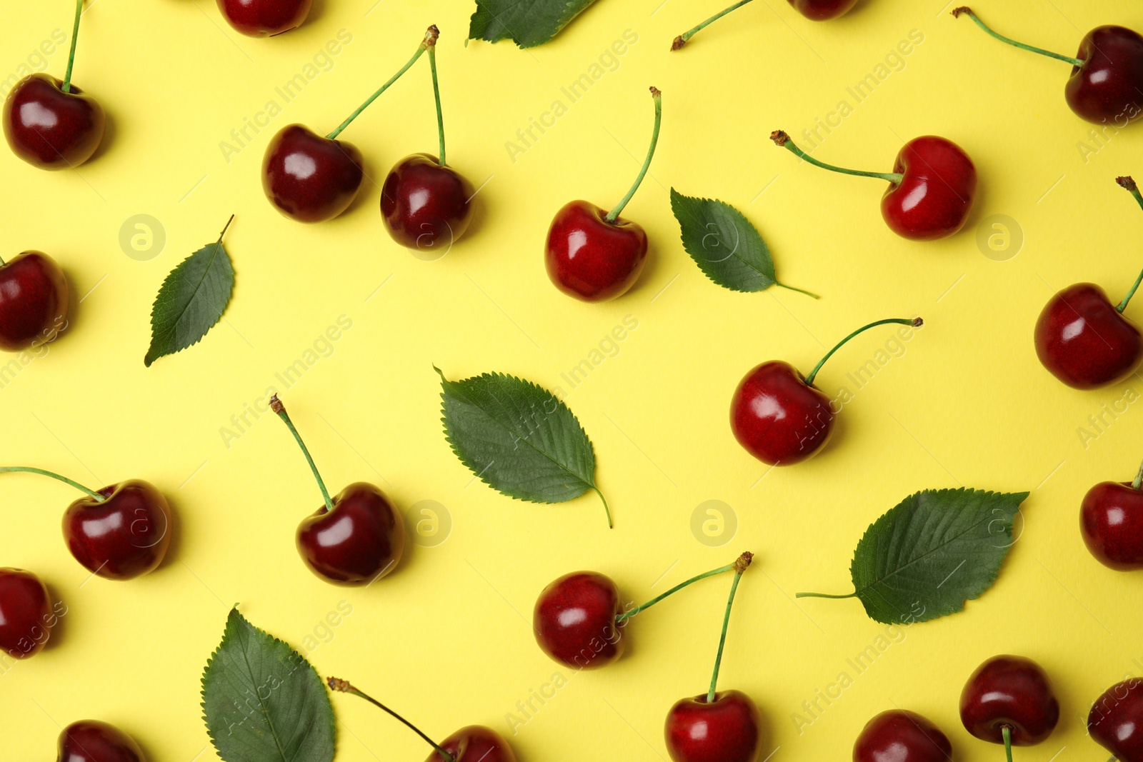 Photo of Many ripe sweet cherries on yellow background, flat lay