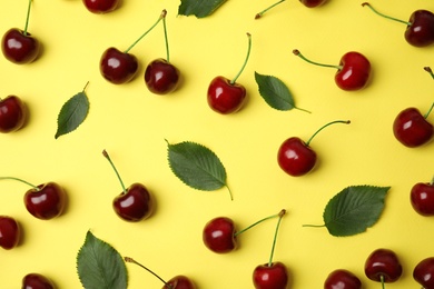 Photo of Many ripe sweet cherries on yellow background, flat lay