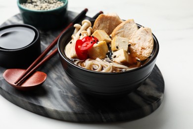 Photo of Delicious ramen served on white table, closeup. Noodle soup