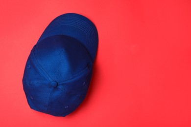 Photo of Stylish blue baseball cap on red background, top view. Space for text