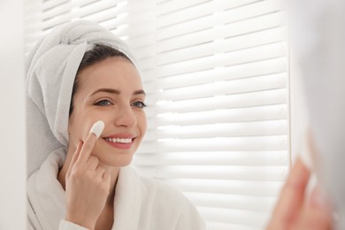 Photo of Woman using silkworm cocoon in skin care routine near mirror at home. Space for text