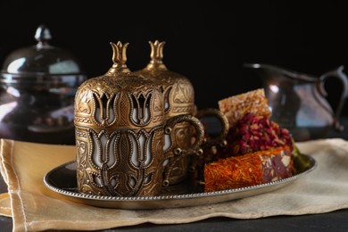 Photo of Tea and Turkish delight served in vintage tea set on black table, closeup