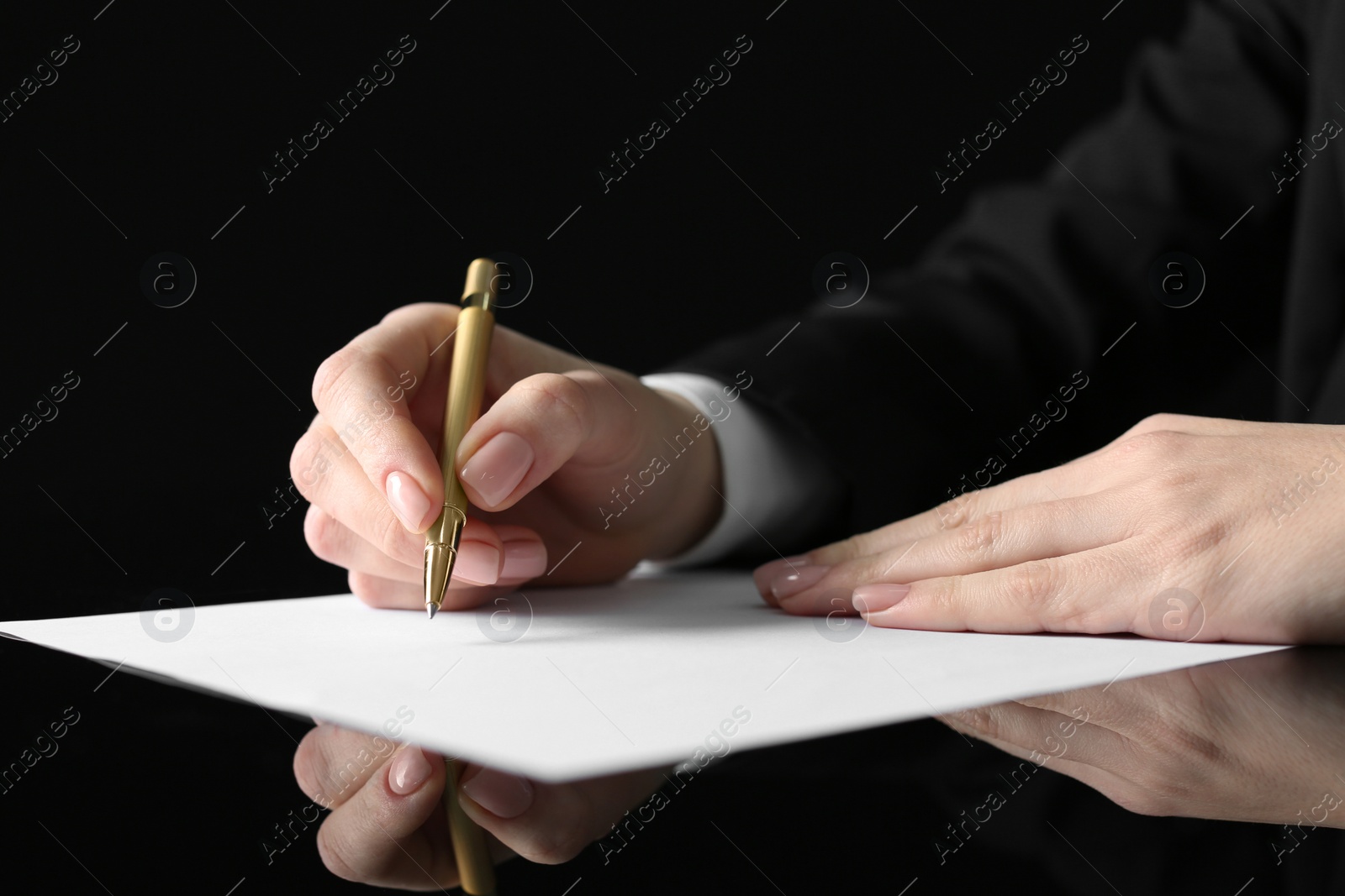 Photo of Woman writing on sheet of paper at glass table, closeup