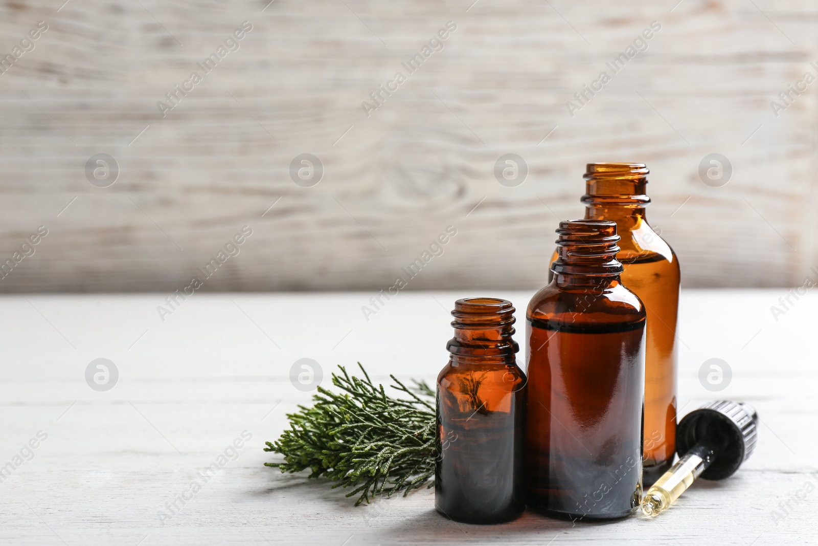 Photo of Composition with bottles of conifer essential oil on white wooden table. Space for text