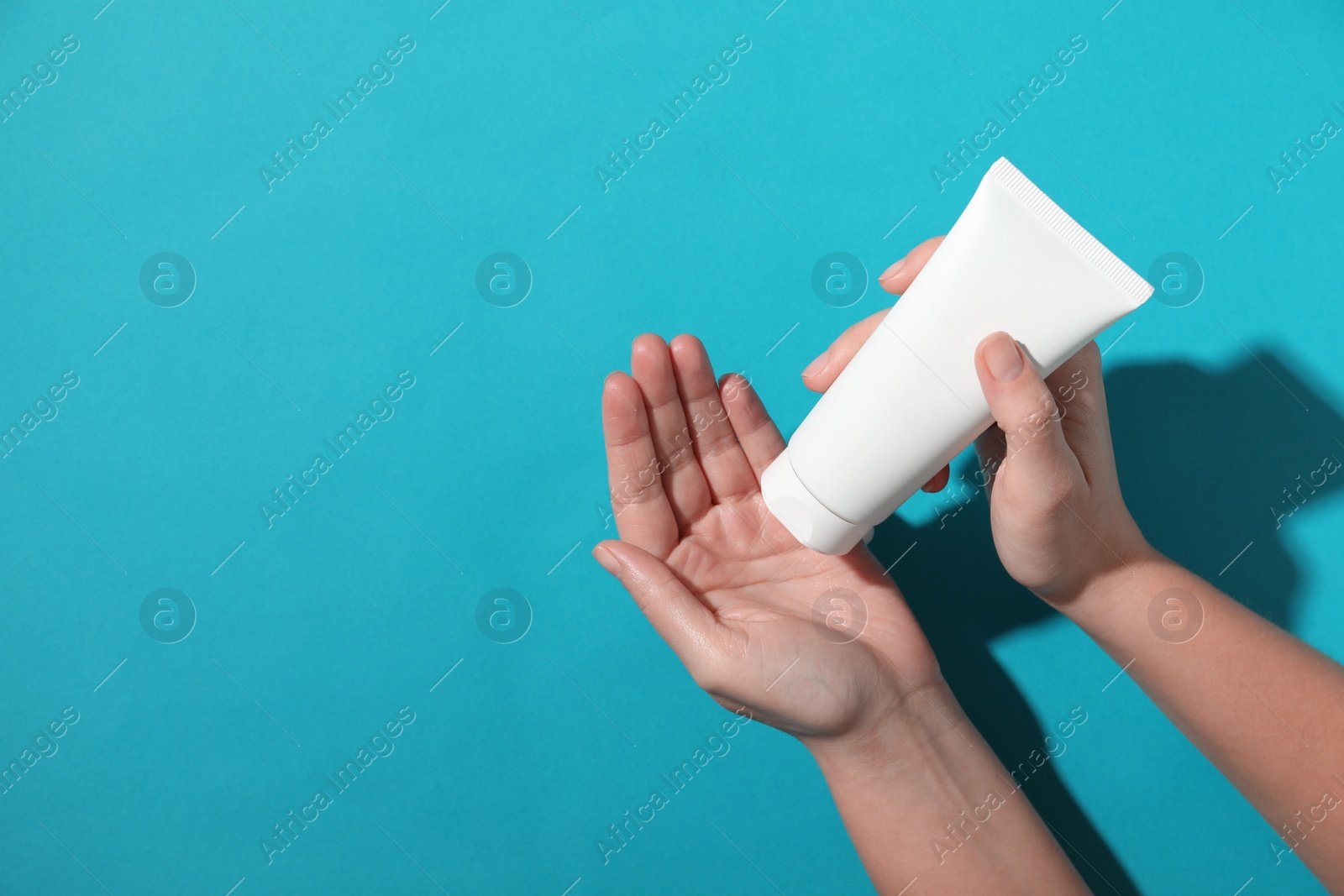 Photo of Woman with tube of hand cream on light blue background, top view. Space for text