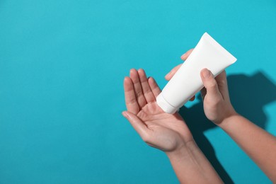 Woman with tube of hand cream on light blue background, top view. Space for text