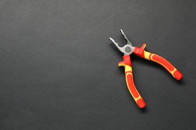Photo of Combination pliers on black background, top view. Space for text