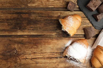 Flat lay composition with tasty croissants and chocolate on wooden table. Space for text