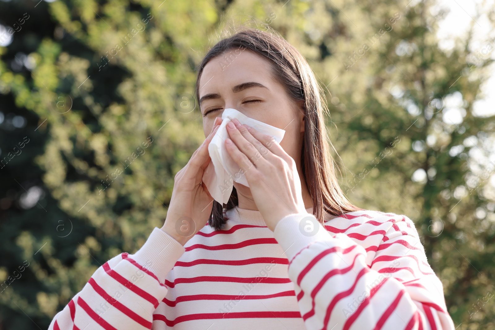 Photo of Woman with napkin suffering from seasonal allergy outdoors