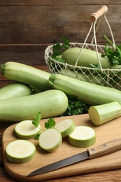 Photo of Cut and whole ripe zucchinis on wooden table