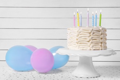 Delicious cake with burning candles and festive decor on white table. Space for text