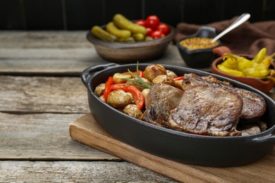 Tasty beef tongue pieces with potatoes, pepper and rosemary on wooden table. Space for text