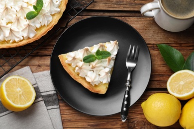 Photo of Piece of delicious lemon meringue pie served on wooden table, flat lay