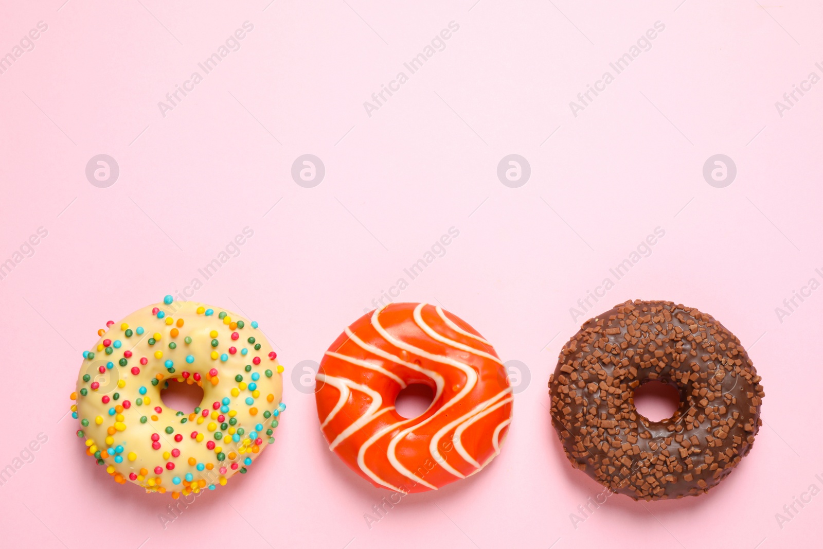 Photo of Delicious glazed donuts on pink background, flat lay. Space for text