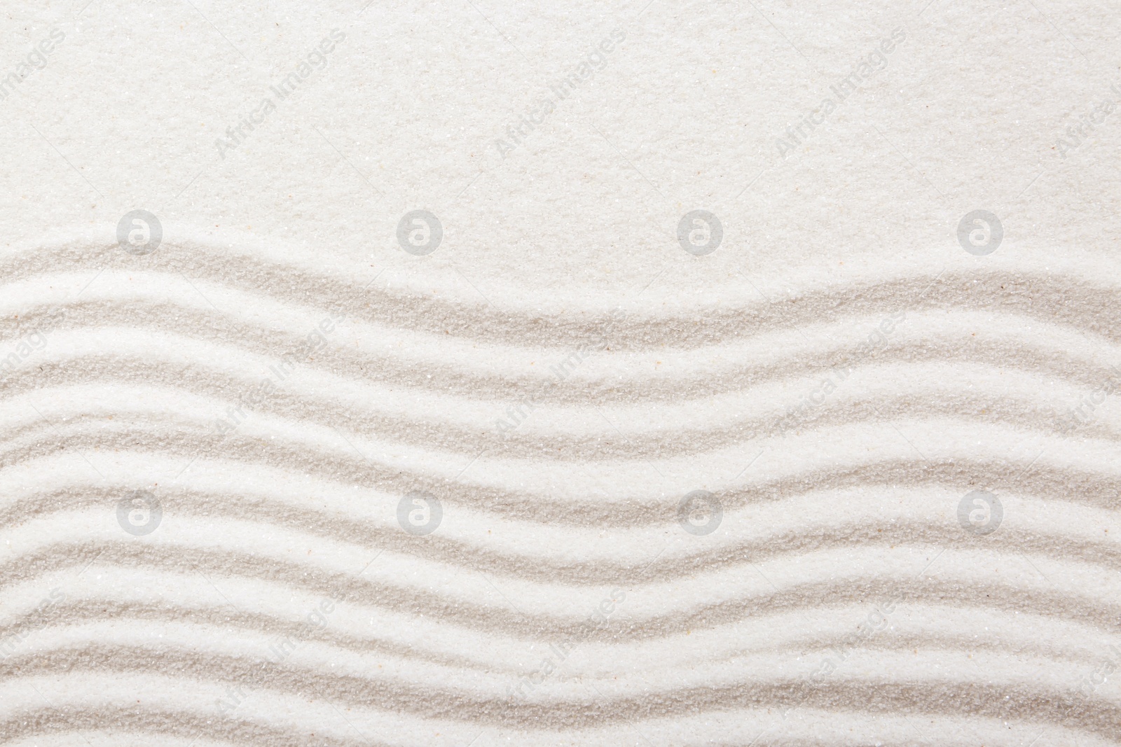 Photo of Zen rock garden. Wave pattern on white sand, top view