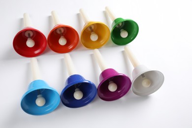 Photo of Set of bright metal hand bells on white background. Montessori musical toy