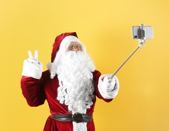 Photo of Authentic Santa Claus taking selfie on yellow background