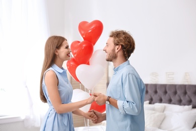 Young couple with air balloons in bedroom. Celebration of Saint Valentine's Day