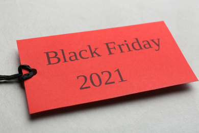 Photo of Red tag with words BLACK FRIDAY 2021 on light grey background, closeup