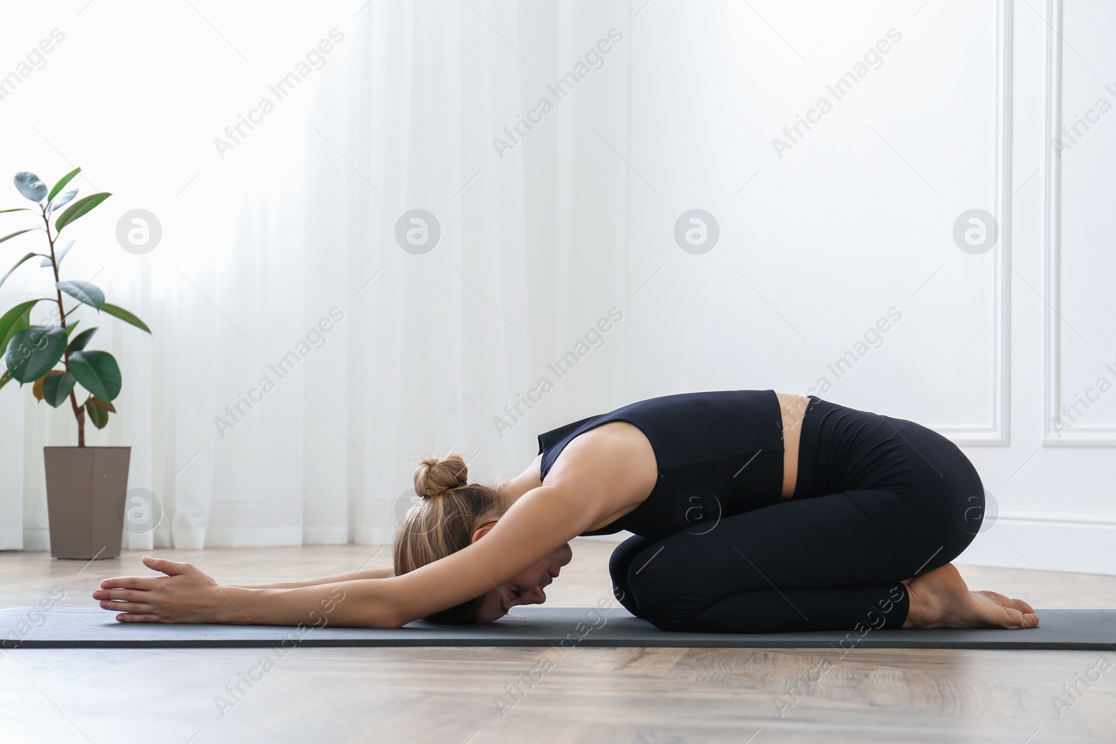 Photo of Young woman practicing extended child asana in yoga studio. Utthita Balasana pose