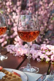 Photo of Glasses of rose wine on table in spring garden