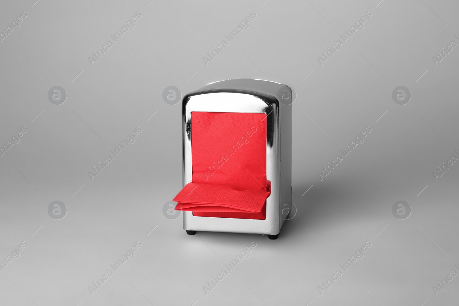 Photo of Napkin holder with paper serviettes on gray background