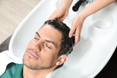 Photo of Stylist washing client's hair at sink in beauty salon