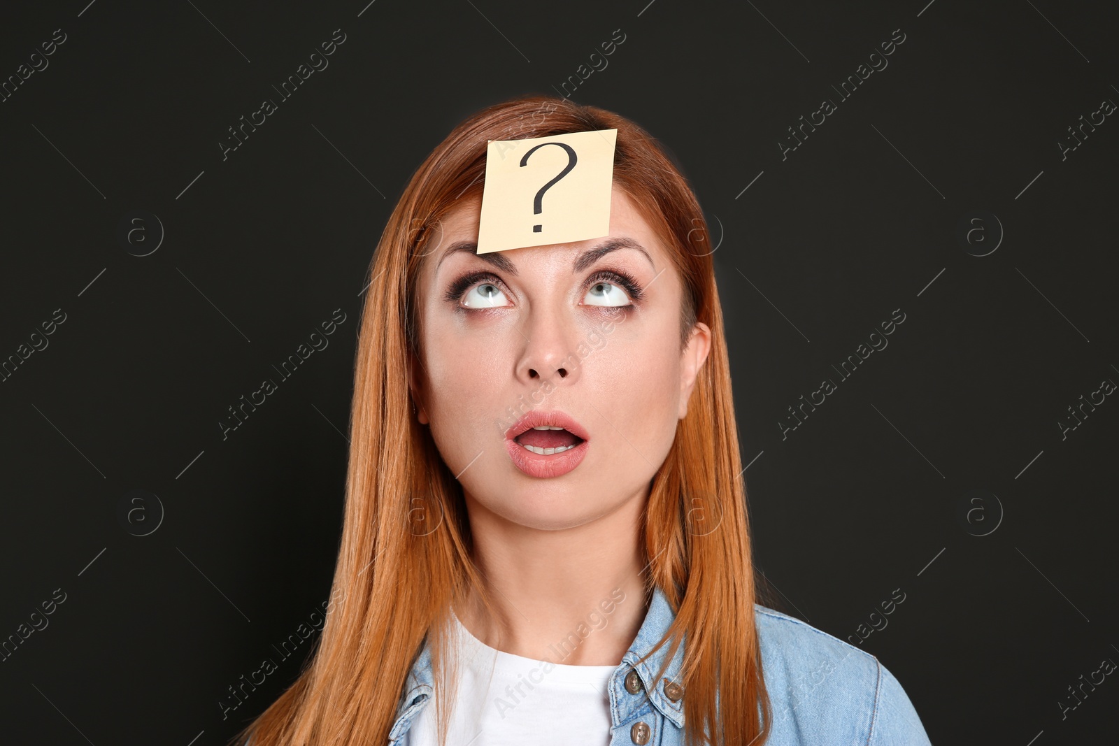 Photo of Emotional woman with question mark sticker on forehead against black background