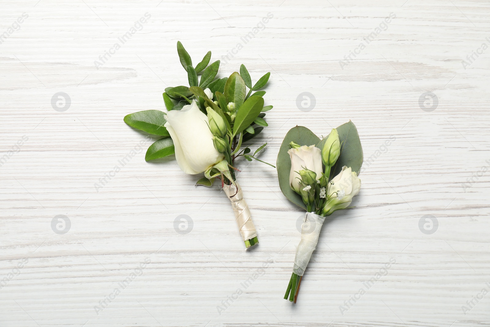 Photo of Wedding stuff. Stylish boutonnieres on white wooden table, top view
