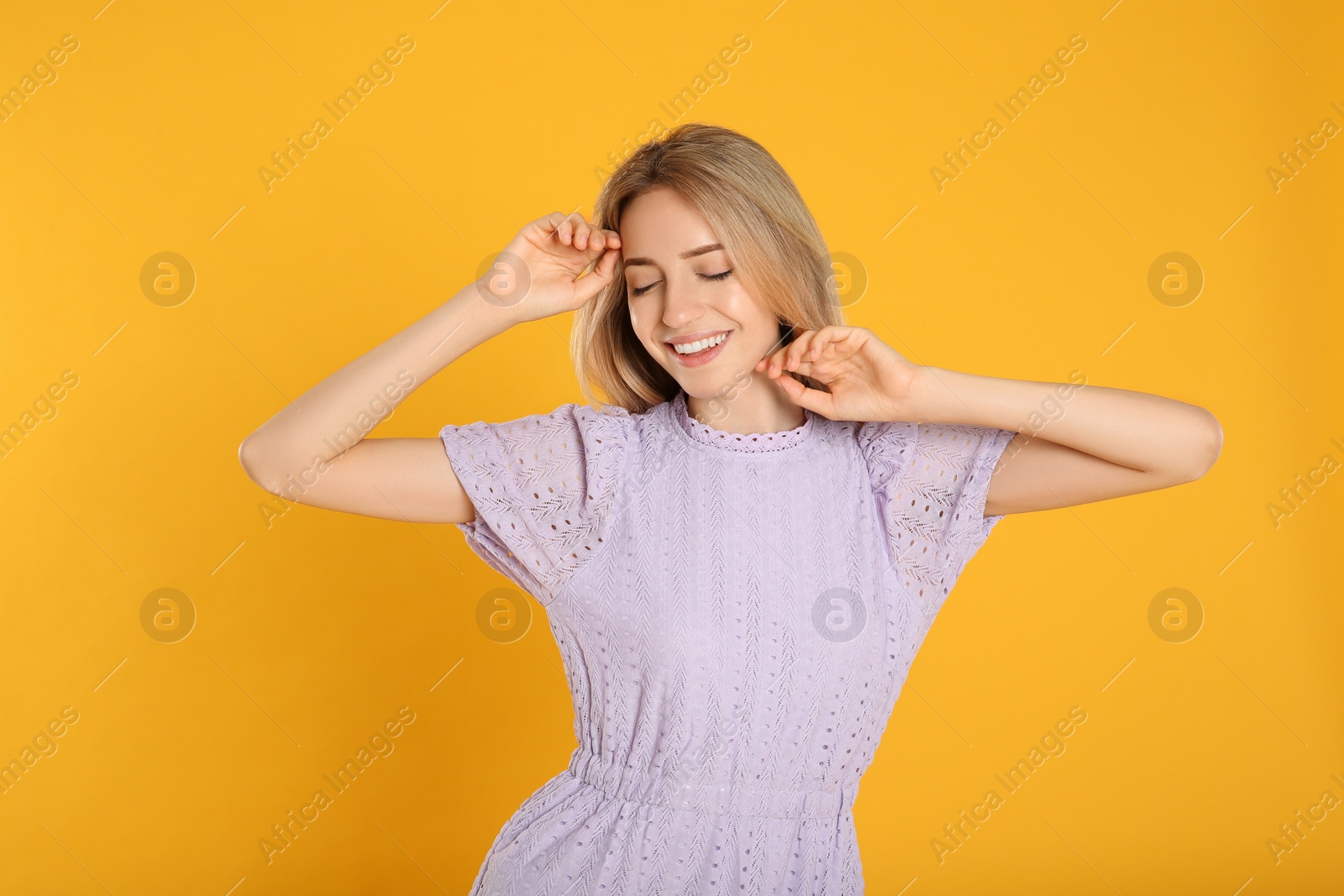 Photo of Portrait of beautiful young woman with blonde hair on yellow background