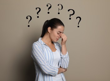 Amnesia. Confused young woman and question marks on beige background