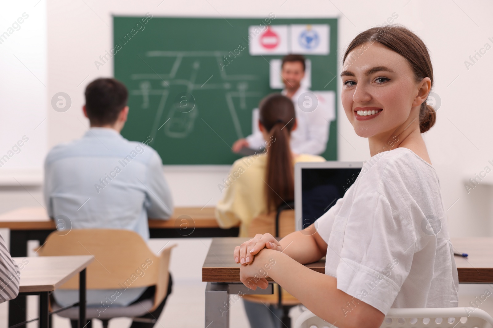 Photo of Happy woman at desk in class during lesson in driving school