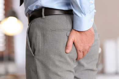 Photo of Man suffering from hemorrhoid in office, closeup