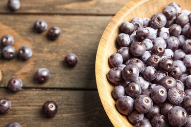 Plate with fresh acai berries on wooden table, closeup