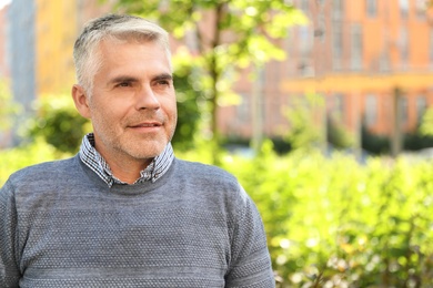 Portrait of handsome mature man in park. Space for text