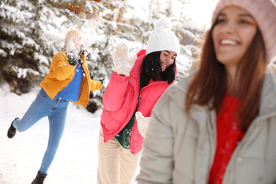 Group of friends playing snowballs outdoors. Winter vacation