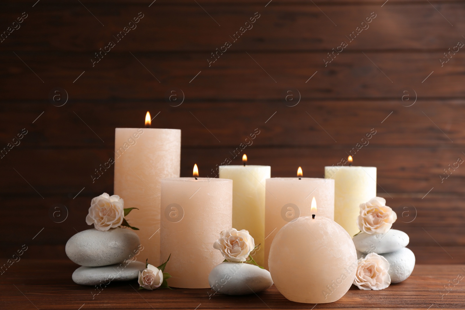 Photo of Composition of burning candles, spa stones and flowers on table. Space for text