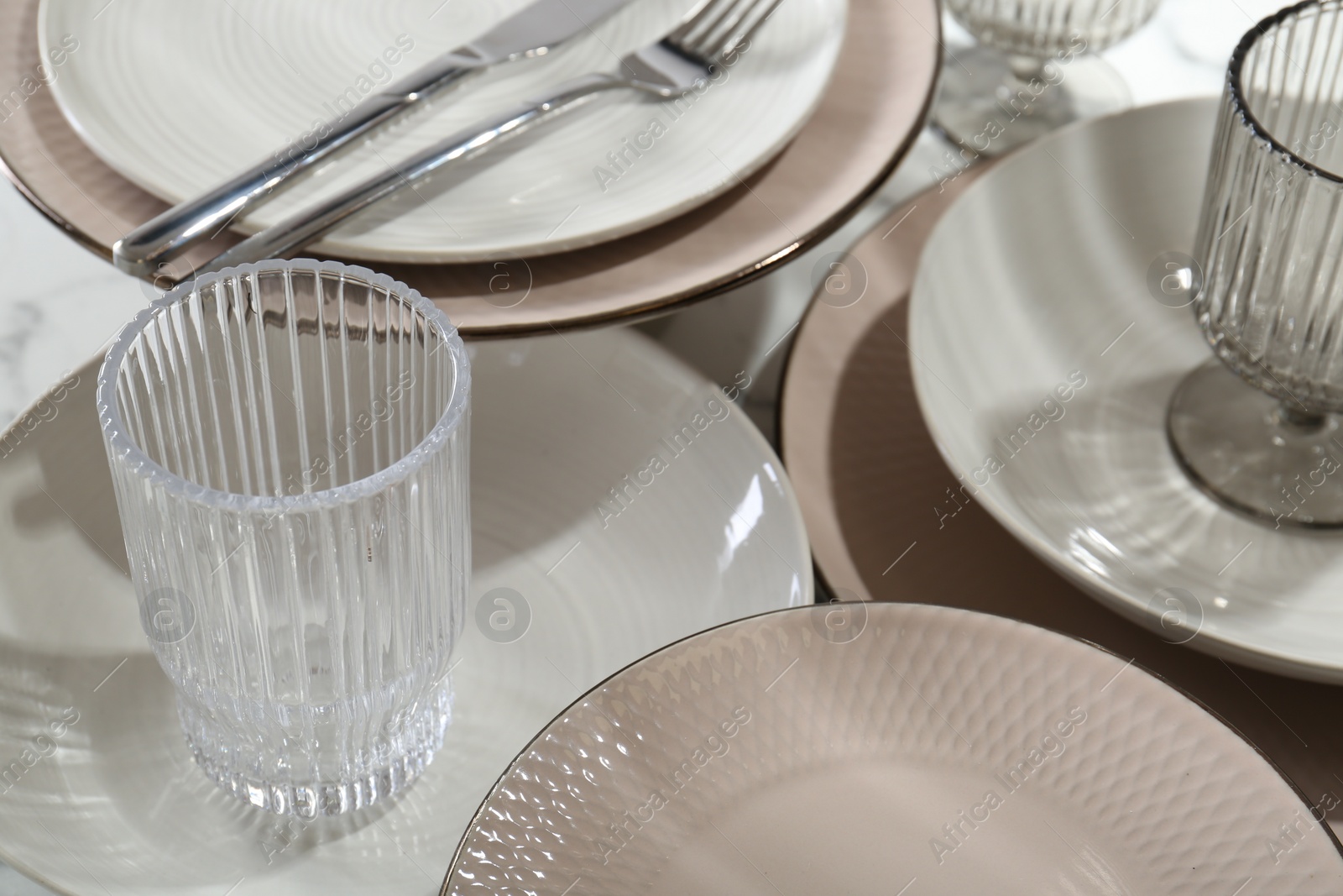 Photo of Stylish ceramic plates, cutlery and glasses on table, closeup