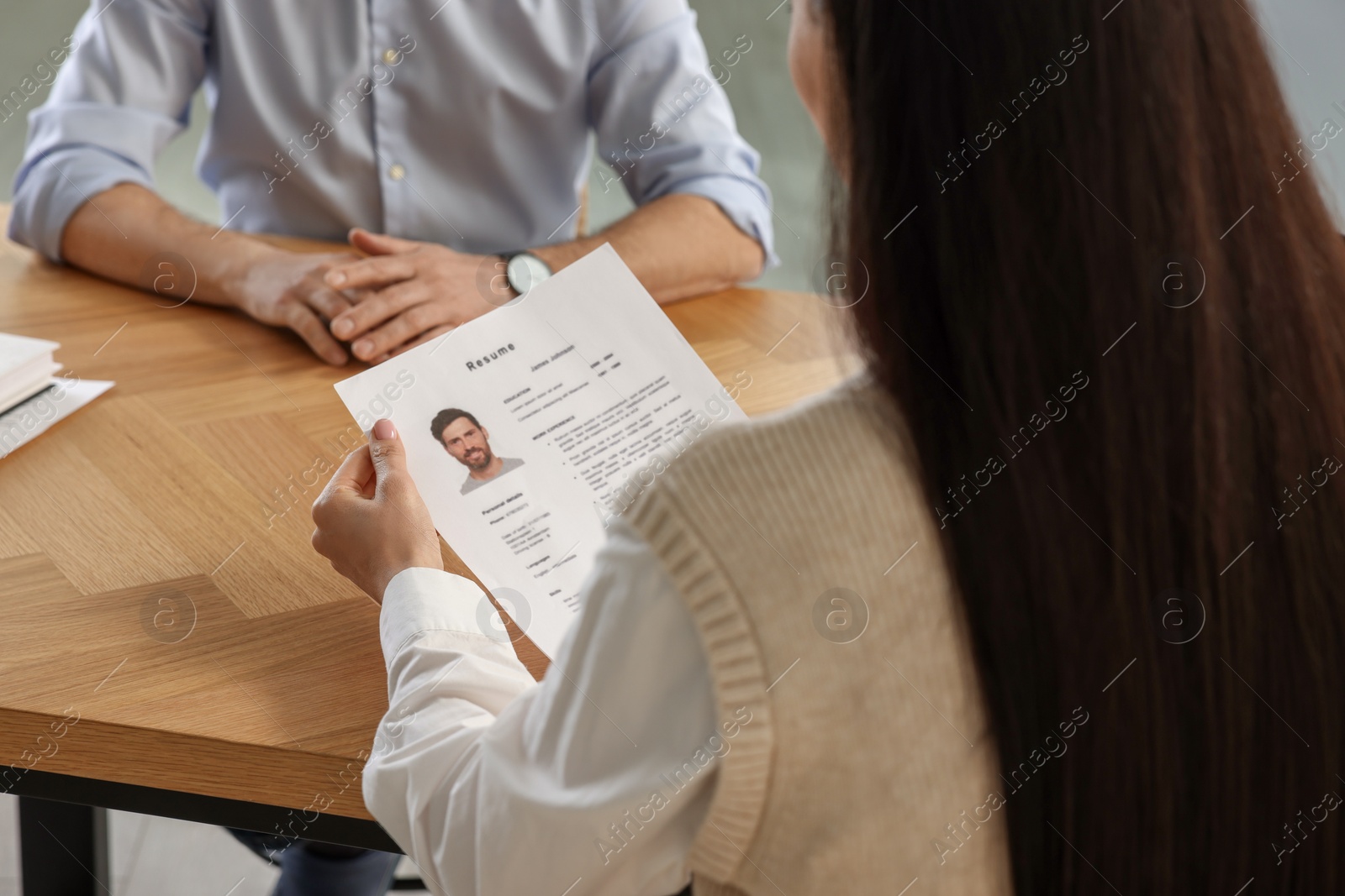 Photo of Human resources manager reading applicant's resume in office, closeup