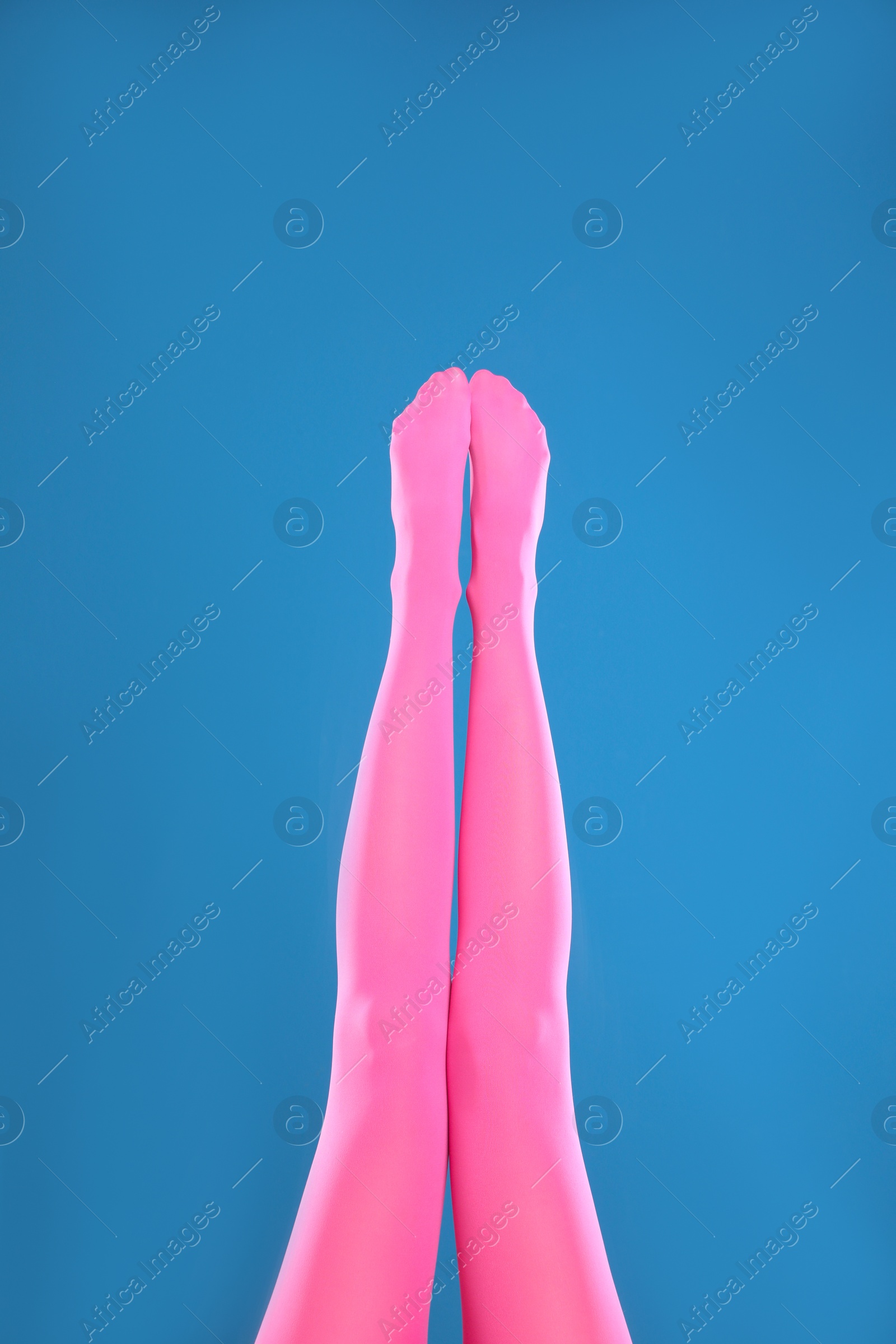 Photo of Woman wearing pink tights on blue background, closeup of legs