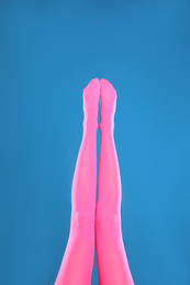 Photo of Woman wearing pink tights on blue background, closeup of legs