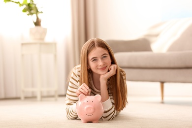 Teen girl with piggy bank and money at home