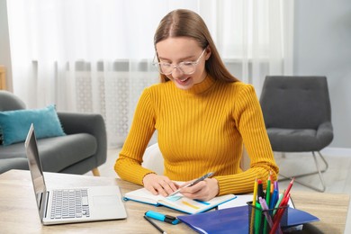 Photo of Woman taking notes at wooden table in office