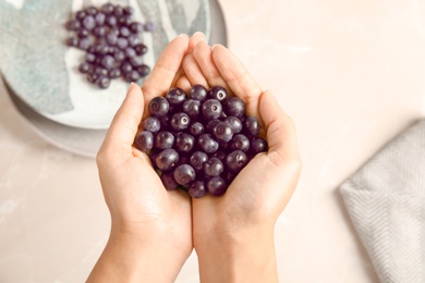 Photo of Woman holding fresh acai berries over table, top view