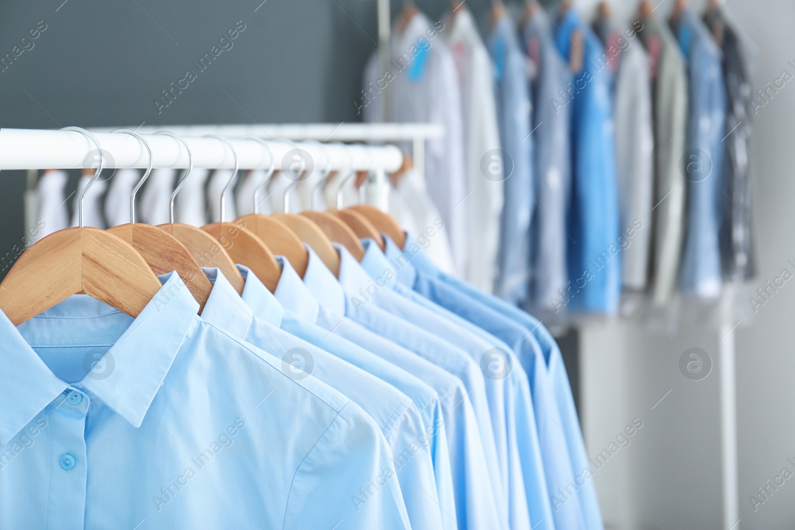 Photo of Rack with clean clothes on hangers after dry-cleaning indoors