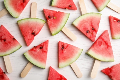 Photo of Watermelon slices with wooden sticks on white background, flat lay
