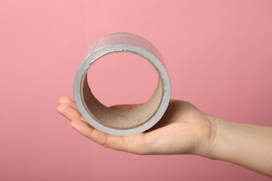 Photo of Woman holding adhesive tape on pink background, closeup