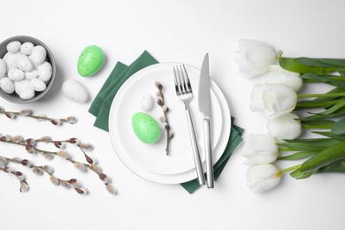 Photo of Festive table setting with tulips and willow twigs on white background, flat lay. Easter celebration
