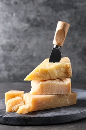 Parmesan cheese with board and knife on grey table